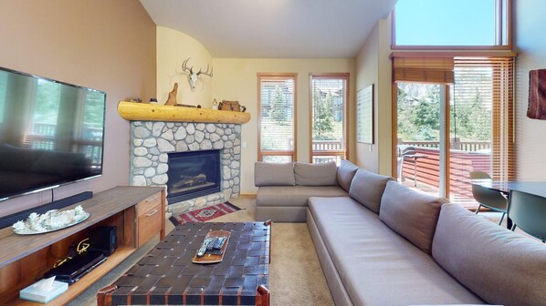 A living room with a stone fireplace, a large flat-screen TV, a sofa, and a coffee table.