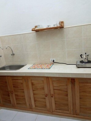 Una cocina con un lavabo, armarios de madera, una encimera y una cafetera.