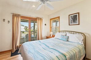 A bedroom with a bed, a ceiling fan, a window with curtains, and a framed picture on the wall.