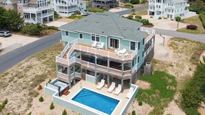 Una casa de dos pisos con piscina, varios balcones y una terraza cubierta.