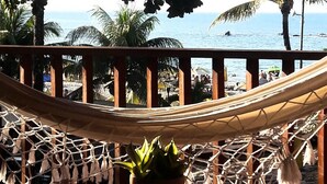 A hammock on a wooden deck with a potted plant and a small round table. - Pousada Funny (Cairu)