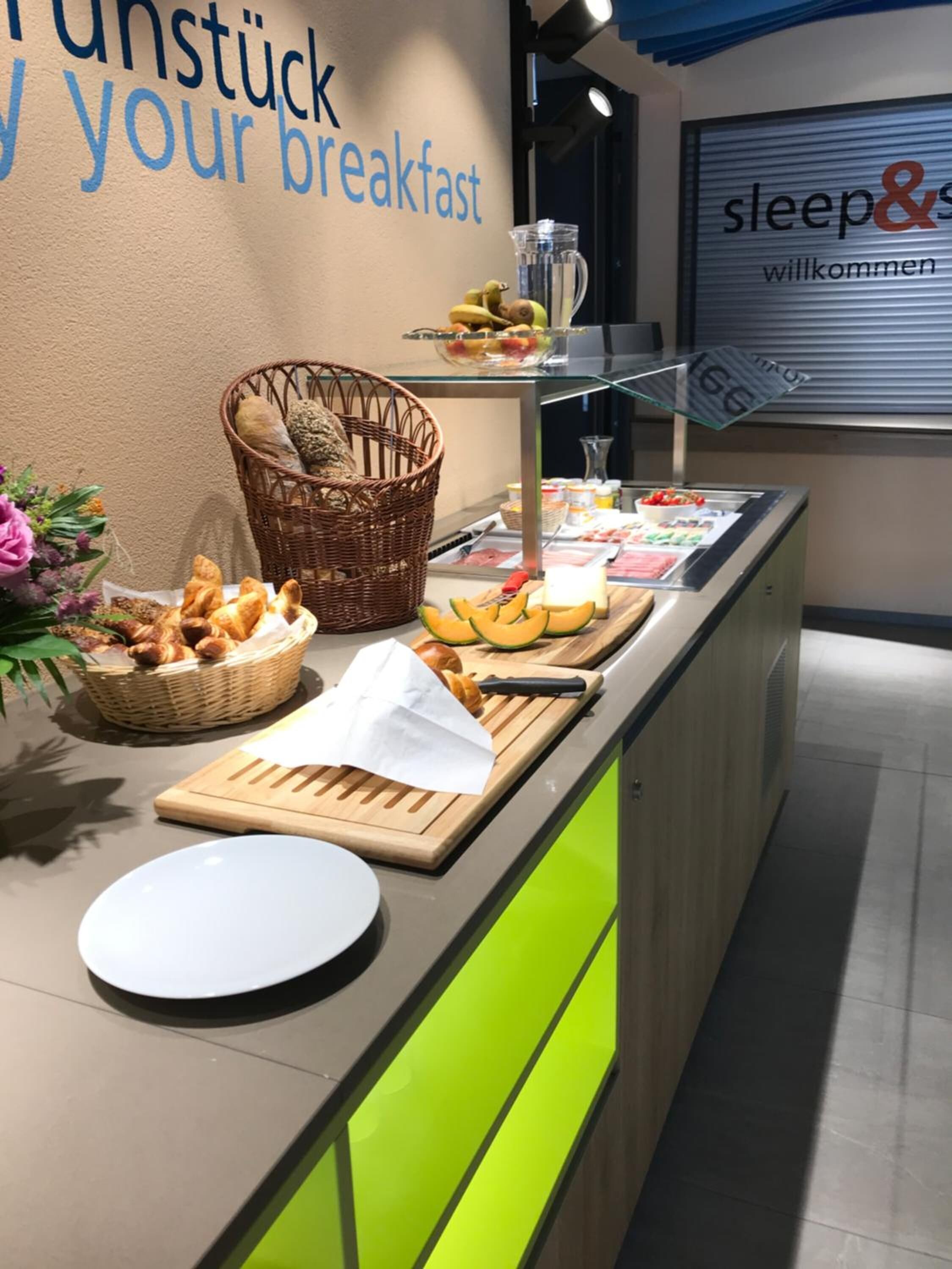 Un bufé de desayuno con diferentes alimentos, una cesta de pan y un letrero que dice "sleep&".