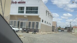 A building with a sign reading "Porto Empresarial Centro de Convênios e Eventos" and a paved street in front. - Pousada Porto Brasil (Pocoes)