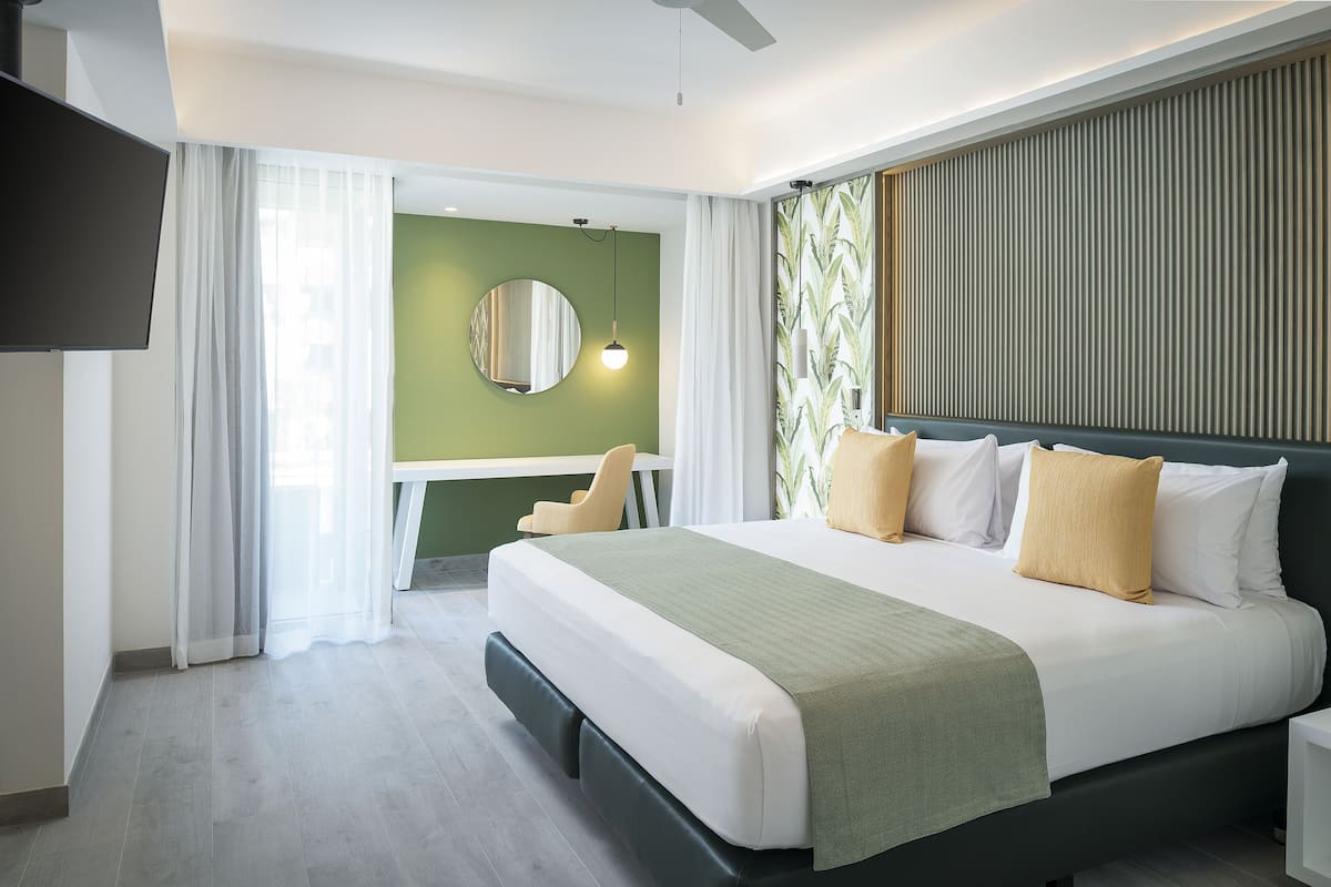 Ein modernes Hotelzimmer mit einem großen Bett, einem Schreibtisch und Blick auf die Stadt.