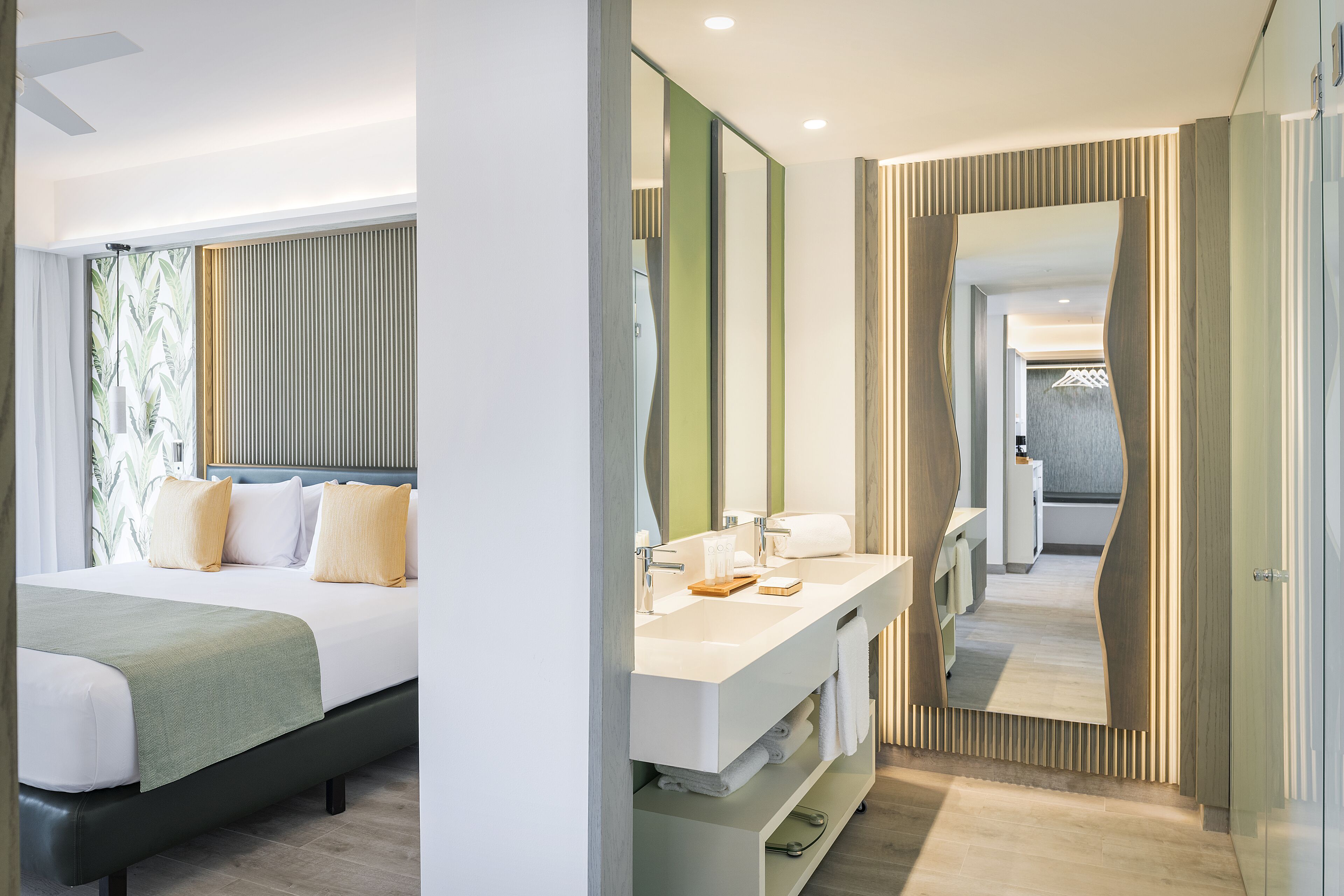 Una habitación de hotel moderna con una cama, un lavamanos en el baño y un espejo.