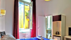A hotel room with a bed, a small table, a TV, and a wardrobe. - NIK King Rooms (Rome)