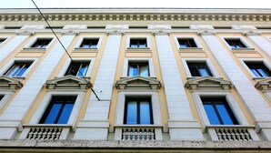 A multi-story building with a classical architectural style, featuring evenly spaced windows and decorative balustrades. - NIK King Rooms (Rome)