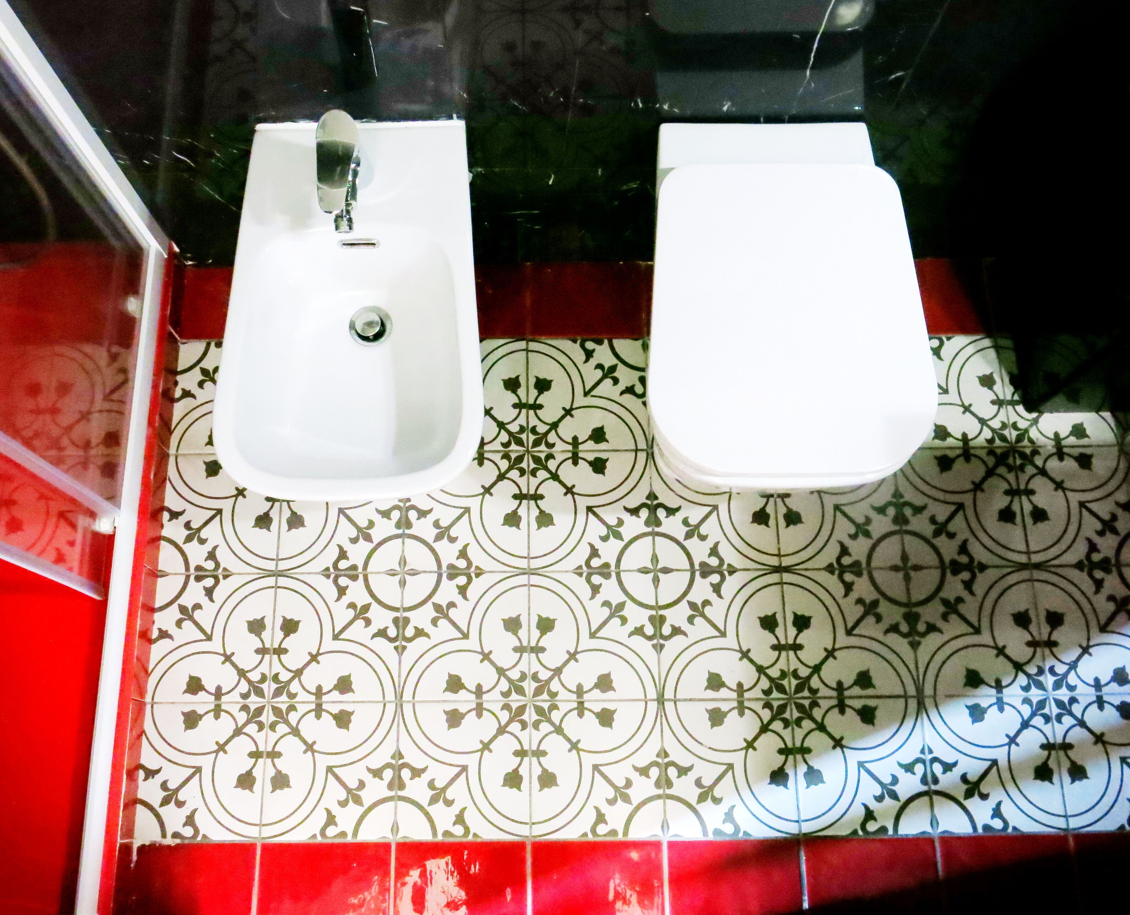 A bathroom with two sinks, a mirror, and patterned tiles.