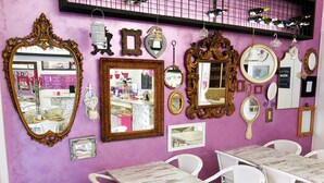A room with purple walls, white wicker furniture, and various mirrors and picture frames on the wall. - NIK King Rooms (Rome)