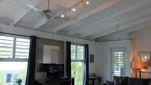 A living room with a television, a sofa, a coffee table, and a ceiling fan.