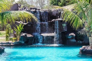 A naturalistic water feature with cascading water over rocks, surrounded by tropical vegetation. - Hotel Pousada Sertão Veredas (Buritizeiro)