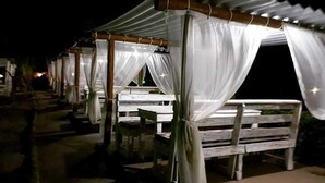 Une rangée d’espaces de détente en plein air, dotés de parasols blancs et de bancs, qui font probablement partie d’un complexe hôtelier ou d’un hôtel.