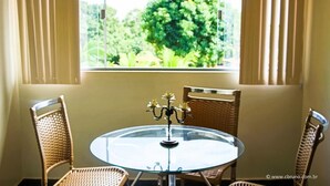 Un coin repas comprenant une table ronde en verre, deux chaises en osier et un chandelier servant de centre de table.