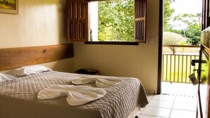 Une chambre à coucher avec un lit, une fenêtre et une vue sur la verdure.