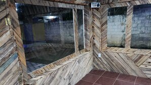 Una habitación con paredes de madera y piso de baldosas, que cuenta con un ventanal grande y una radio.