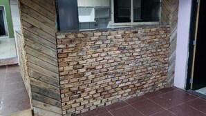 Una habitación con pared de ladrillo, ventana y suelo de baldosas.