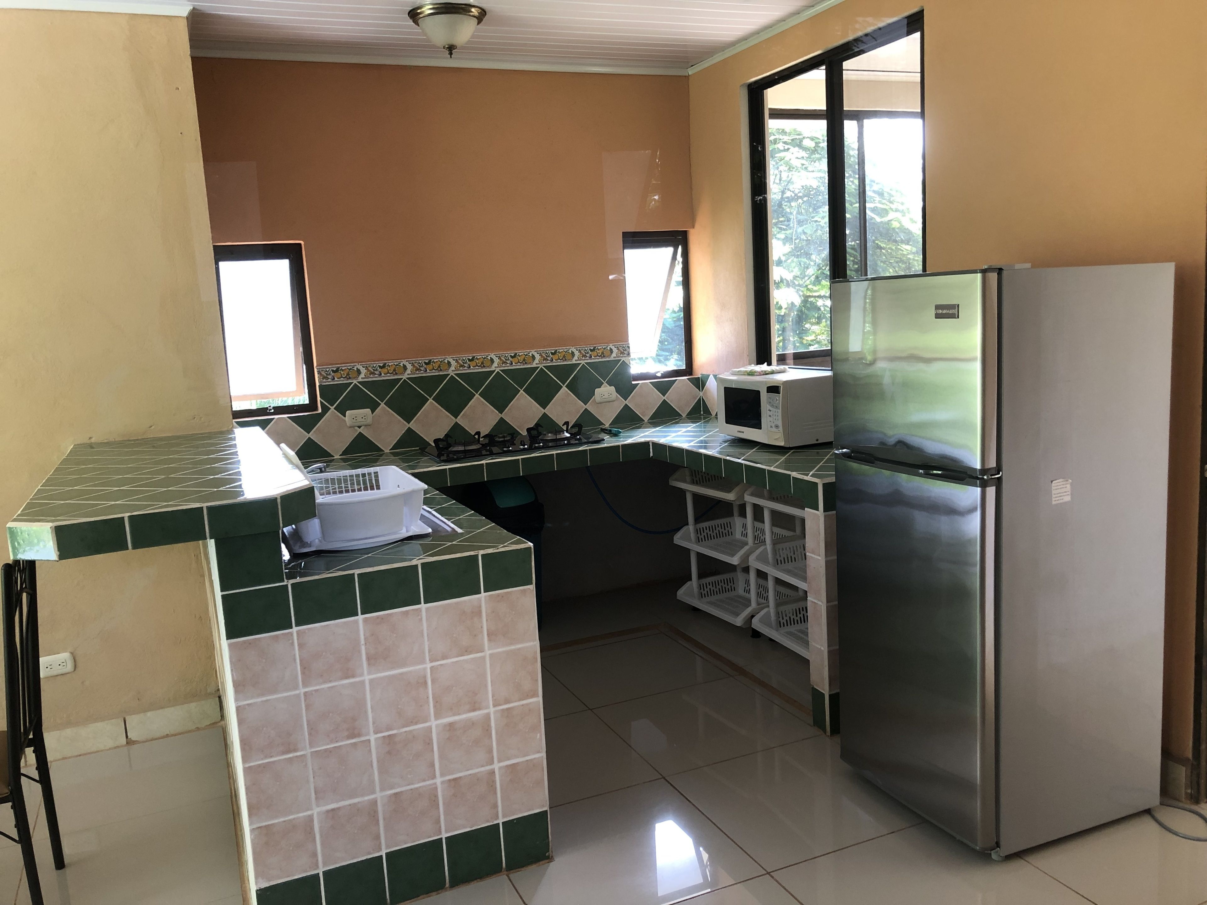 A kitchen with a refrigerator, microwave, and gas stove.