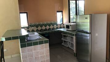 A kitchen with a refrigerator, microwave, and gas stove.