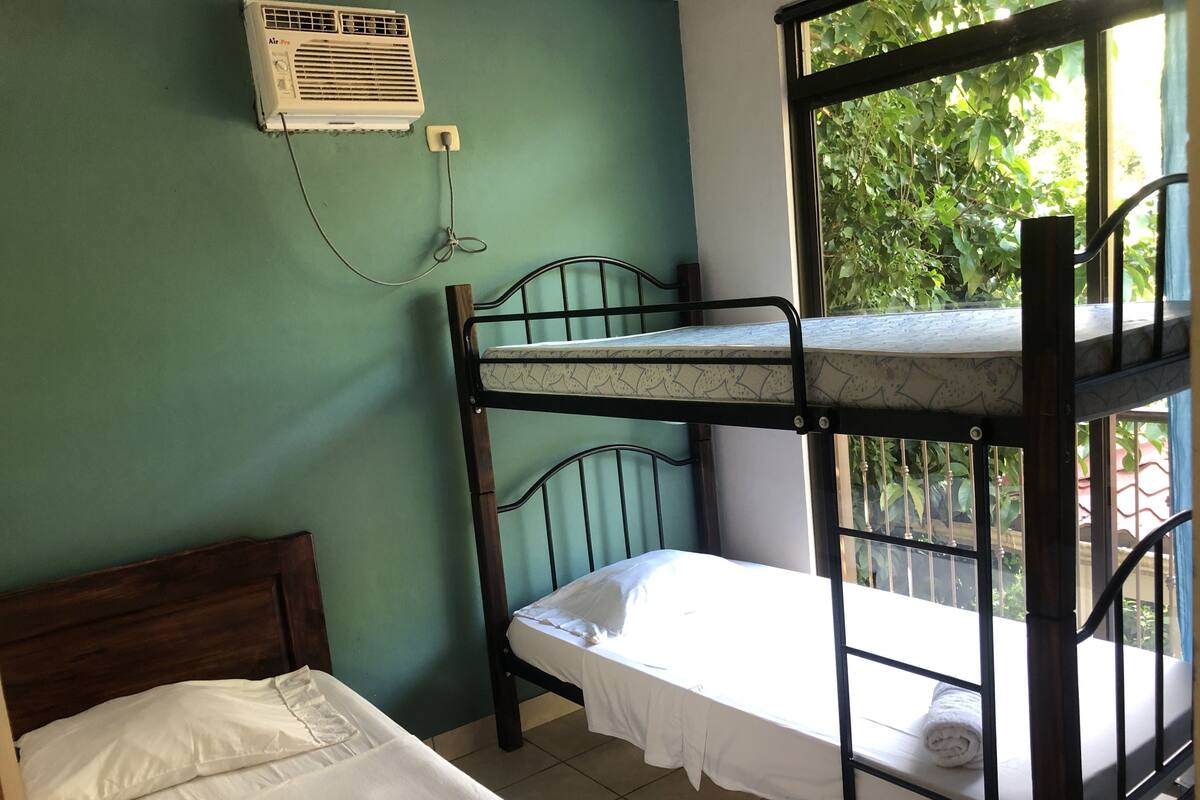 A bunk bed room with a single bed and an air conditioner on the wall.