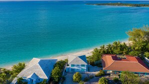 Um imóvel costeiro com praia, casa de telhado vermelho e vista clara para o oceano.