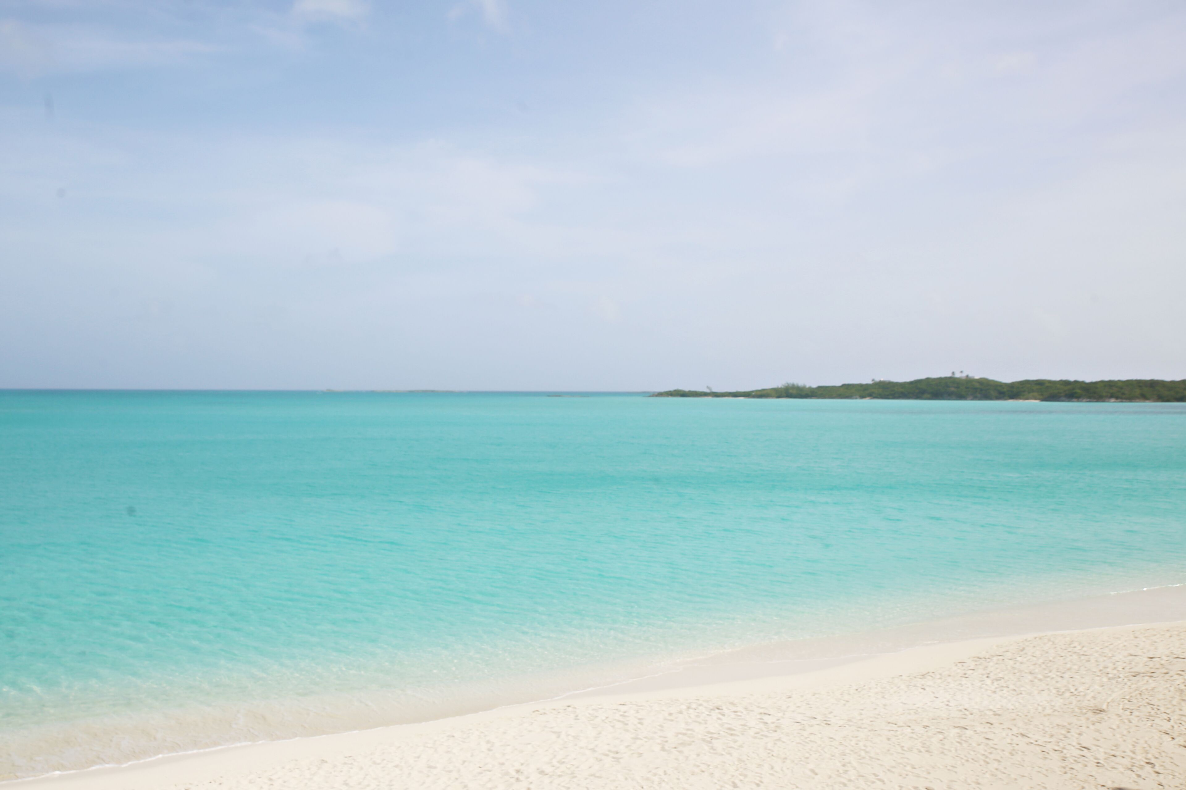 A beach with clear turquoise water and a sandy shore.