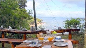 A table set for breakfast with a view of the beach and ocean. - Pousada VillaBahia (Cairu)