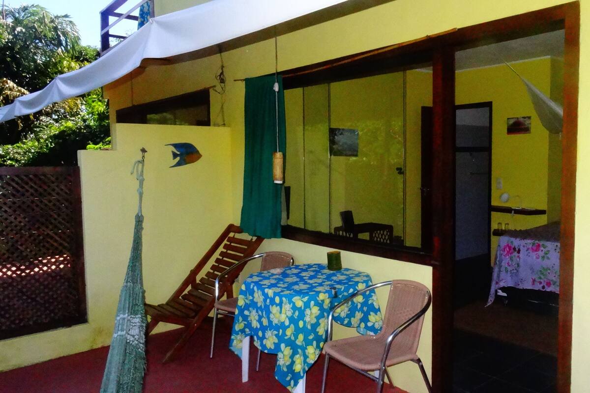 Un espace extérieur aménagé en terrasse, avec une table et des chaises, un petit escalier et une grande fenêtre.