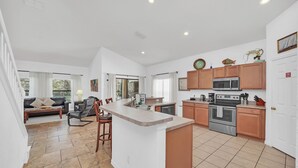 A spacious kitchen with a central island, wooden cabinets, and modern appliances. - 6 miles to WDW: 4 Bedroom/3+ Bath, Private Pool/Hot Tub, Wifi, Game Room, Clean (Kissimmee)