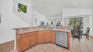 A modern kitchen with a large island, wooden cabinets, and a dishwasher. - 6 miles to WDW: 4 Bedroom/3+ Bath, Private Pool/Hot Tub, Wifi, Game Room, Clean (Kissimmee)