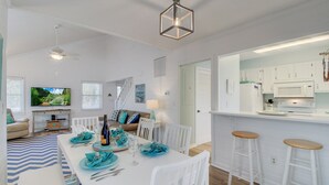 A modern kitchen with white cabinets, a built-in oven, and a bar area with stools. - 72 Pelican Bay | AvantStay | Community Pool, Decks (Isle of Palms)
