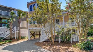 A residential building with a covered walkway, palm trees, and a well-maintained garden. - 72 Pelican Bay | AvantStay | Community Pool, Decks (Isle of Palms)