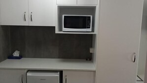Une petite cuisine équipée d’un four à micro-ondes, d’un petit réfrigérateur et d’un placard contenant une boîte de mouchoirs.