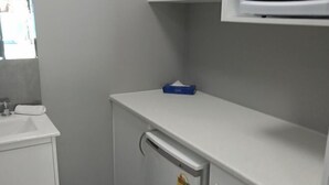 Une petite salle de bain avec un lavabo blanc, un miroir et un meuble blanc au-dessus.