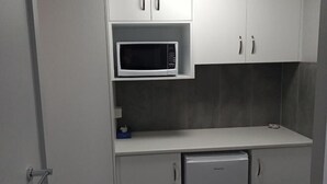 Une cuisine compacte équipée d’un four à micro-ondes, d’un petit réfrigérateur et de placards.
