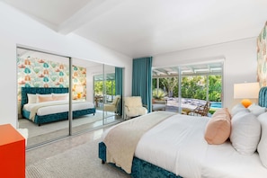 Un dormitorio moderno con una cama grande, un muro de cristal y vistas a una piscina y vegetación.