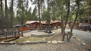 Zona rústica con cabañas de madera, un hogar de piedra y un camino de grava.