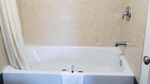A modern bathroom with a bathtub, a toilet, and a shower area. - Travis Lodge Motel 16 (Oakland)