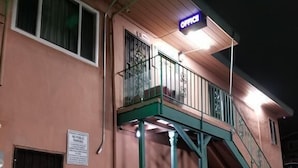 A two-story building with a sign that reads "OFFICE" above the entrance. There is a staircase leading to a balcony on the second floor. - Travis Lodge Motel 16 (Oakland)