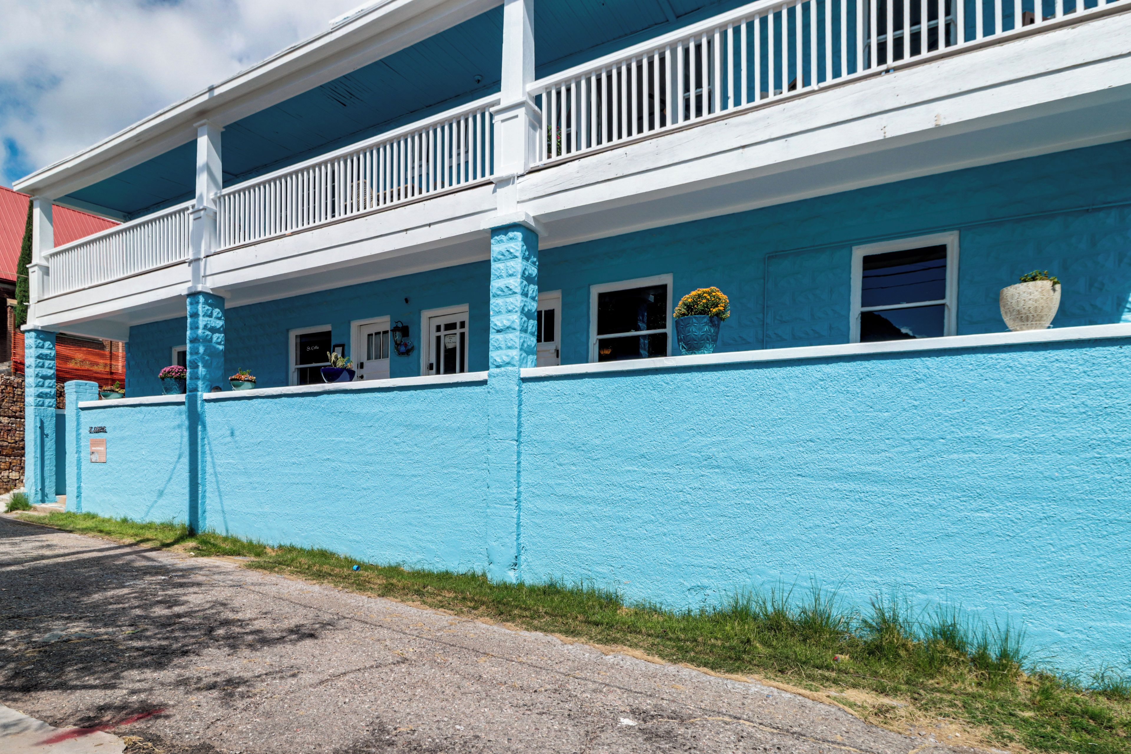 A two-story building with a blue exterior, white railings, and multiple windows.