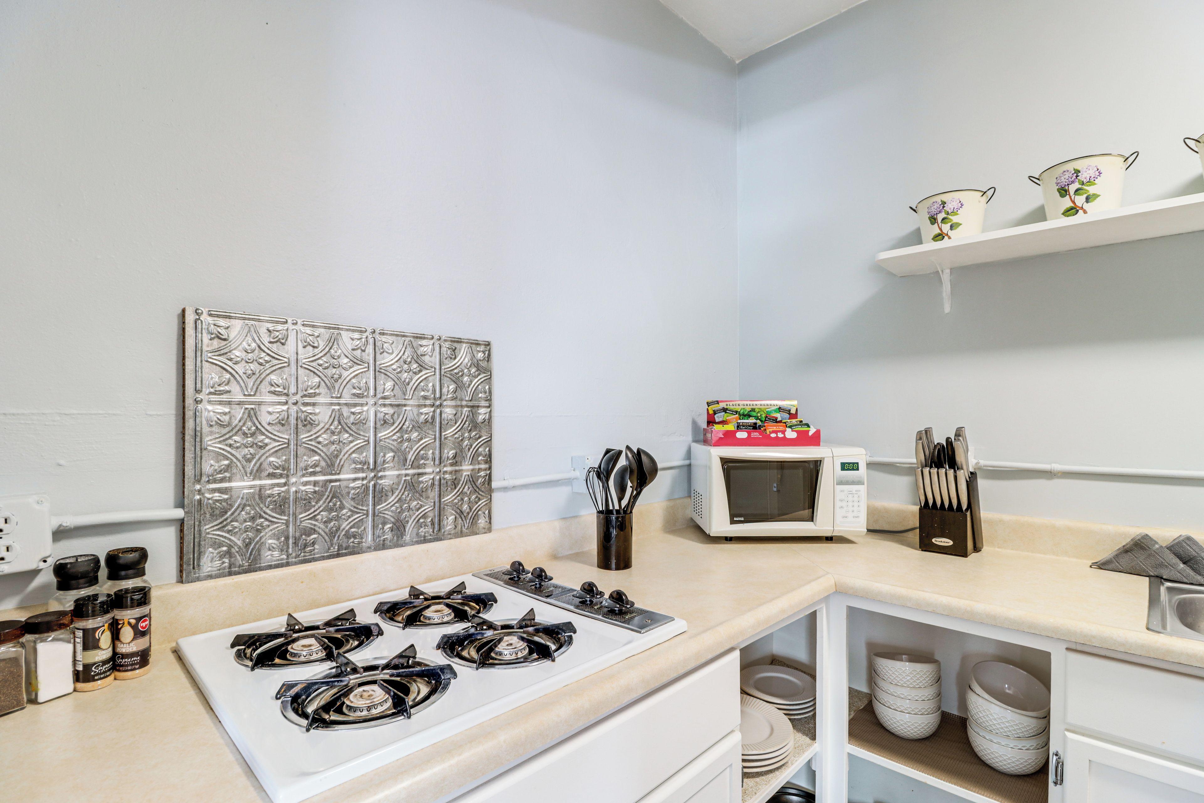 A kitchen with a gas stove, a microwave, and a spice rack.