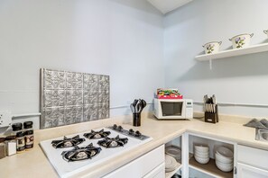 Een keuken met een gasfornuis, een magnetron en een kruidenrek.