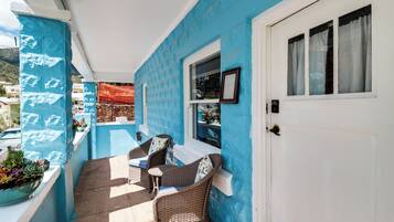 A covered outdoor seating area with wicker furniture and a blue wall.