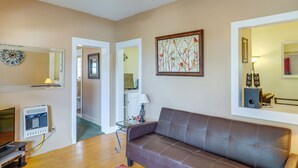 A living room with a brown leather sofa, a clock, a framed artwork, and a mirror reflecting a lamp and speakers. - 'St Ceilia' Apt - Walk to Bisbee Attractions! (Bisbee)