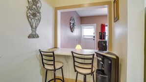 A small kitchen with a white countertop, two bar stools, a refrigerator, and a door leading to a living area. - 'St Ceilia' Apt - Walk to Bisbee Attractions! (Bisbee)