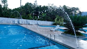Une piscine dotée de jets d’eau, de chaises longues et d’une terrasse en béton.