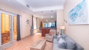 A living room with a sofa, a coffee table, and a dining area with a table and chairs. - Beachfront Luxury at Coral Sands (Roatan)