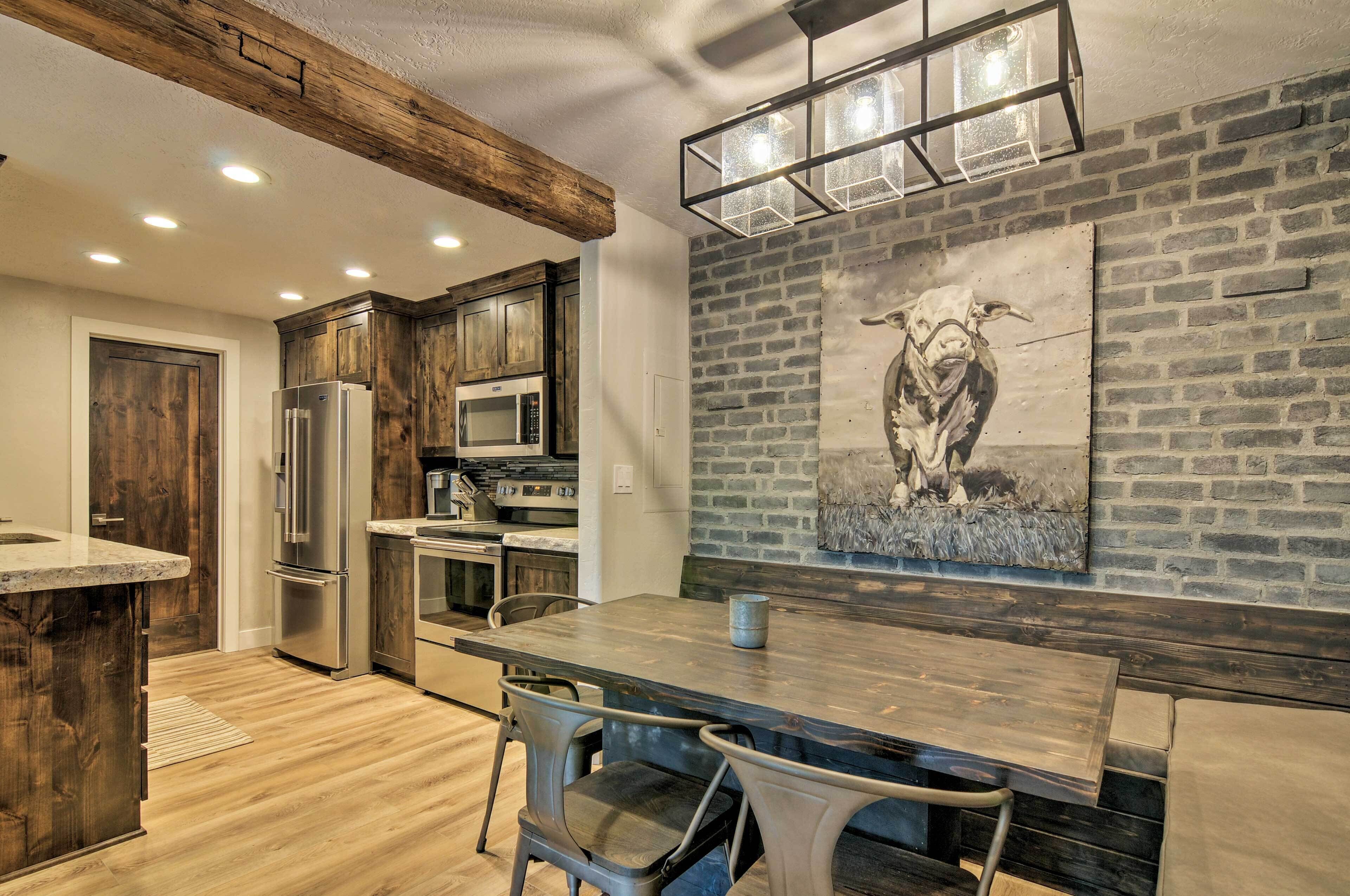 A modern kitchen with wooden cabinets, stainless steel appliances, and a dining area with a wooden table and chairs.