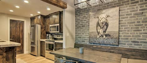 A modern kitchen with wooden cabinets, stainless steel appliances, and a dining area with a wooden table and chairs.