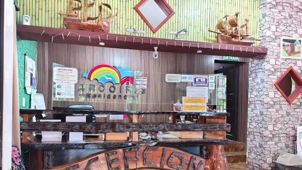 A reception desk with a wooden design, a sign for 'RECEPTION,' and various informational posters. - Arcoíris Residencial (Puerto Iguazú)
