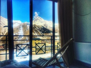 A room with large windows offering a view of snow-capped mountains. - Chemodann Kazbegi (Kazbegi)